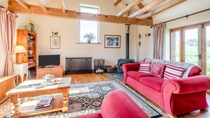 A cozy living room with a red sofa, wooden beams, a fireplace, and a television. - 2 Bed in Dorchester (oc-dc075) (Frome Whitfield)