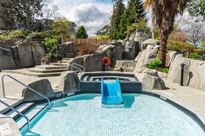 Ein Swimmingpool mit blauer Rutsche, Steinstufen und einem Rettungsring.