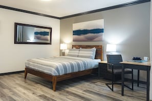 A hotel room with a bed, desk, chair, and two wall-mounted lamps. - Ocean Lookout - Resort Stay with Pool & Hot Tub (Nanoose Bay)