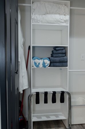 Ein Schrank mit Regalen, einer Kleiderstange und einem Korb.