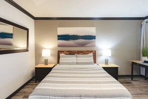 Ein Hotelzimmer mit einem Bett, zwei Nachttischen, einer Lampe, einem Bild und einer Zimmerpflanze.