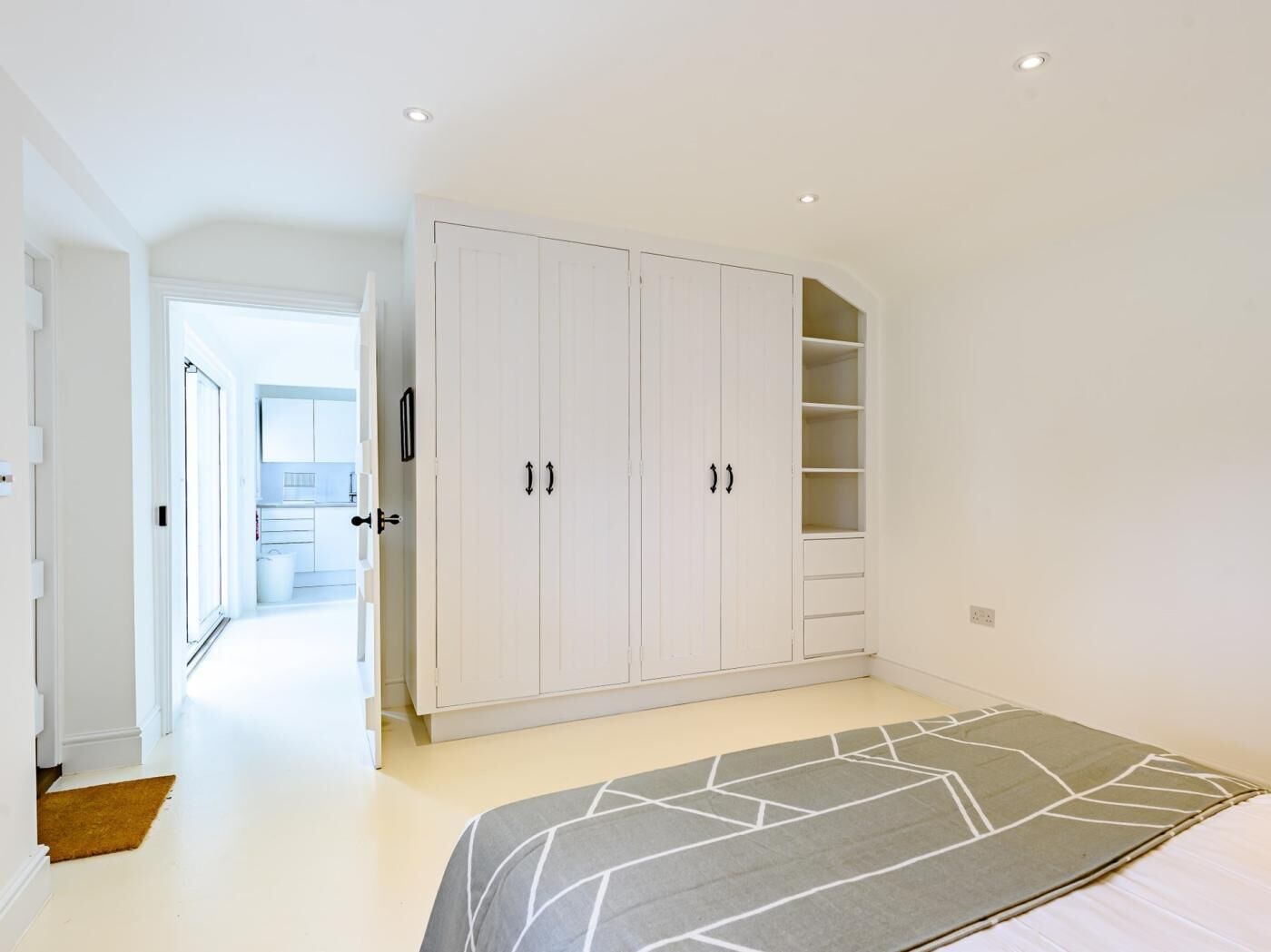 A bedroom with a bed, a wardrobe, and a bathroom visible in the background.