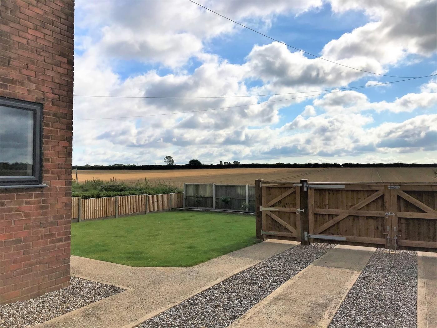 A brick building with a grassy yard and a wooden gate.
