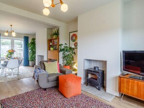 A modern living room with a fireplace, a television, and a dining area with a table and chairs. - 3 Bed in King's Lynn (oc-82358) (Harpley)