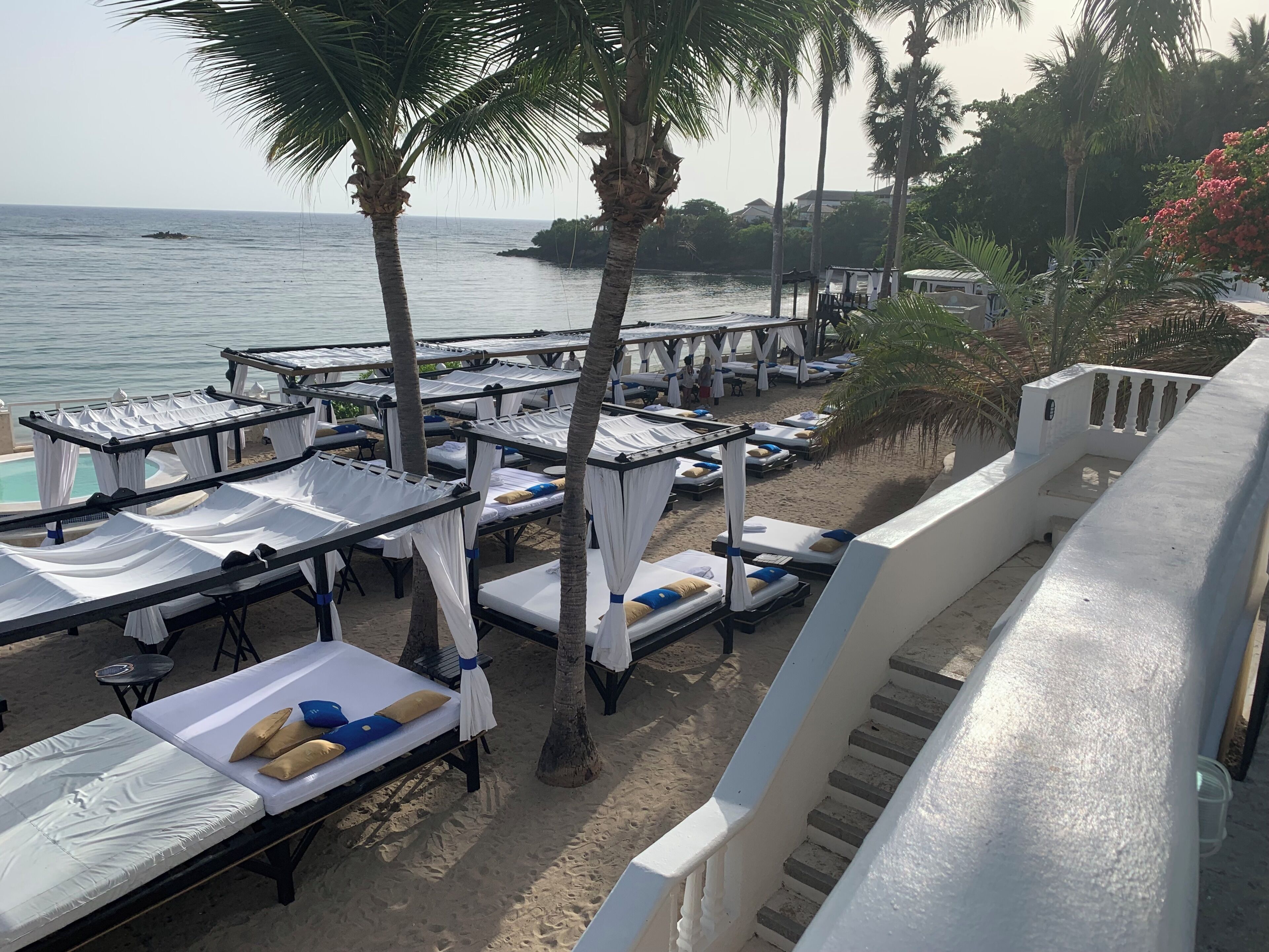A beachside hotel with rows of sunbeds, a pool, and a view of the sea.