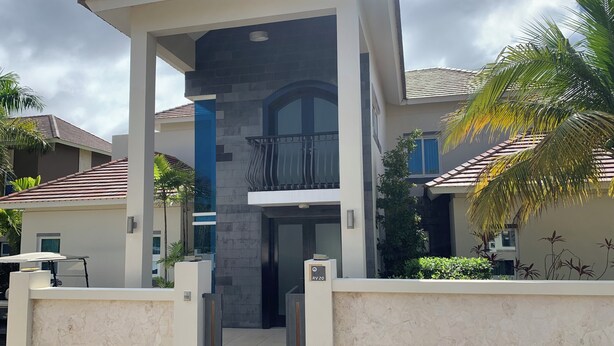 A modern multi-story residential building with a central entrance, a balcony, and a stone facade. - Royal Villa 4-bedroom Villa-January 15, 2027-January 22, 2027 (Cofresi)