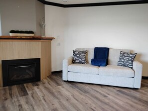 Ein Wohnzimmer mit einer Couch, gemusterten Kissen, einem Kamin und Holzboden.