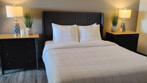 Ein Hotelzimmer mit einem großen Bett, zwei Nachttischen mit Lampen, einem dunklen Kopfteil und je einem kleinen Blumentopf auf jedem Tisch.