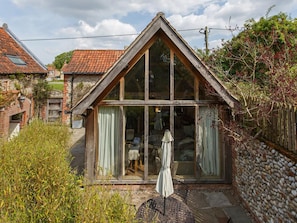 A small, single-story house with a steeply pitched roof and large windows. - 2 Bed in Holt (oc-ncc39) (Cley next the Sea)