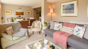 A living room with a sofa, armchairs, a coffee table, and a lamp. - 5 Bed in Hunstanton (oc-kt185) (Sedgeford)