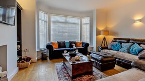 Ein Wohnzimmer mit Sofa, Couchtisch, Lampe und einem Fenster mit Jalousien.