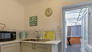 Eine Küche mit Mikrowelle, Spüle, Schränken, einer Uhr und einer Karte an der Wand.