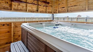 En stuga byggd av trä med ett bubbelbad och en träveranda.