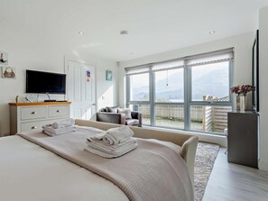 A bedroom with a bed, a TV, a dresser, a chair, and a balcony with a view. - 1 Bed in Crieff (oc-58797) (Saint Fillans)