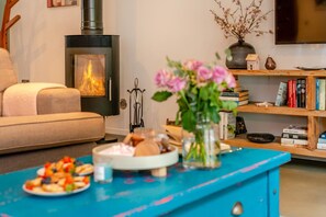 Ein gemütliches Wohnzimmer mit Kamin, einer Couch, einem Couchtisch mit Essen und einem Bücherregal.