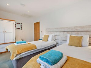 Ein Hotelzimmer mit zwei Betten, einem Kleiderschrank und einem Spiegel an der Wand.
