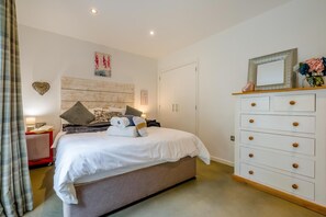 Une chambre à coucher comprenant un lit, une commode, une table de chevet et un mur orné d’un décor en forme de cœur.