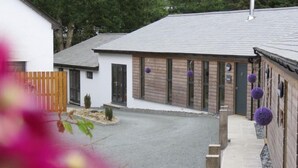 A building with a paved driveway, a wooden fence, and a small garden area. - 2 Bed in Holsworthy (oc-50598) (Sessacott)