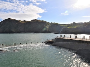 A coastal scene with a pier extending into calm waters, surrounded by rocky cliffs and a clear sky. - 1 Bed in Ilfracombe (oc-90074) (Ilfracombe)