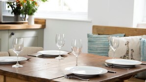 A dining table set with plates, glasses, and cutlery. - 6 Bed in Ilfracombe (oc-52585) (Combe Martin)