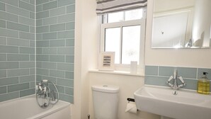 A bathroom with a toilet, sink, and bathtub. - 6 Bed in Ilfracombe (oc-52585) (Combe Martin)