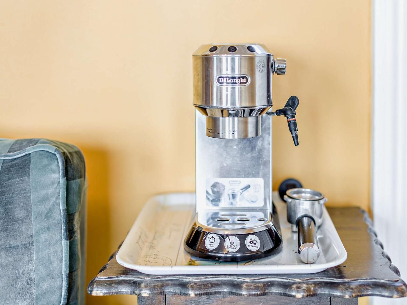 Una macchina per espresso DeLonghi su un tavolo di legno con un vassoio.