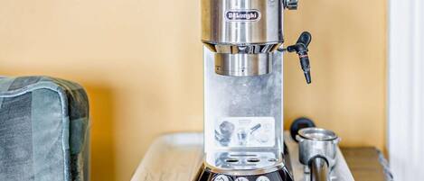 Una macchina per espresso DeLonghi su un tavolo di legno con un vassoio.