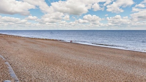 Ein Kiesstrand bei klar blauem Himmel und ruhiger See.