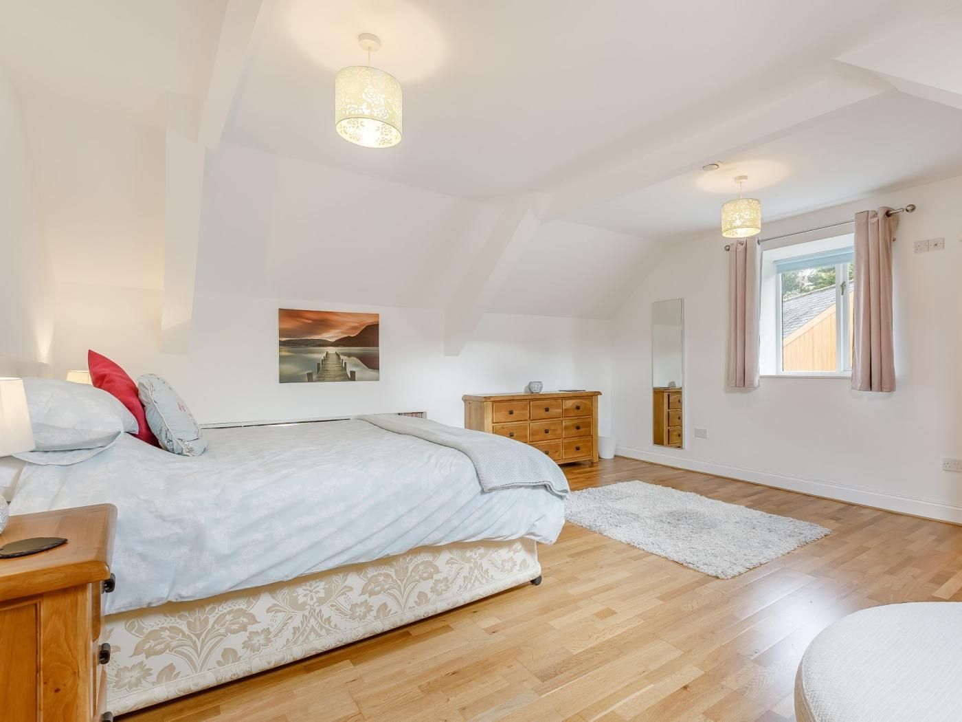 Ein Schlafzimmer mit einem Bett, einem Schminktisch, einem Spiegel und einem Fenster mit Vorhängen.
