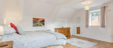 Ein Schlafzimmer mit einem Bett, einem Schminktisch, einem Spiegel und einem Fenster mit Vorhängen.