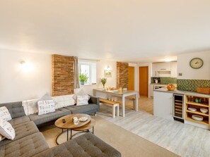 A modern living room with a sofa, a coffee table, and a dining area with a table and chairs. - 3 Bed in Ilfracombe (oc-47348) (Berrynarbor)