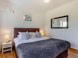 A bedroom with a bed, bedside lamps, a nightstand, a framed picture, a mirror, and a window. - 1 Bed in Launceston (oc-49662) (Saint Clether)