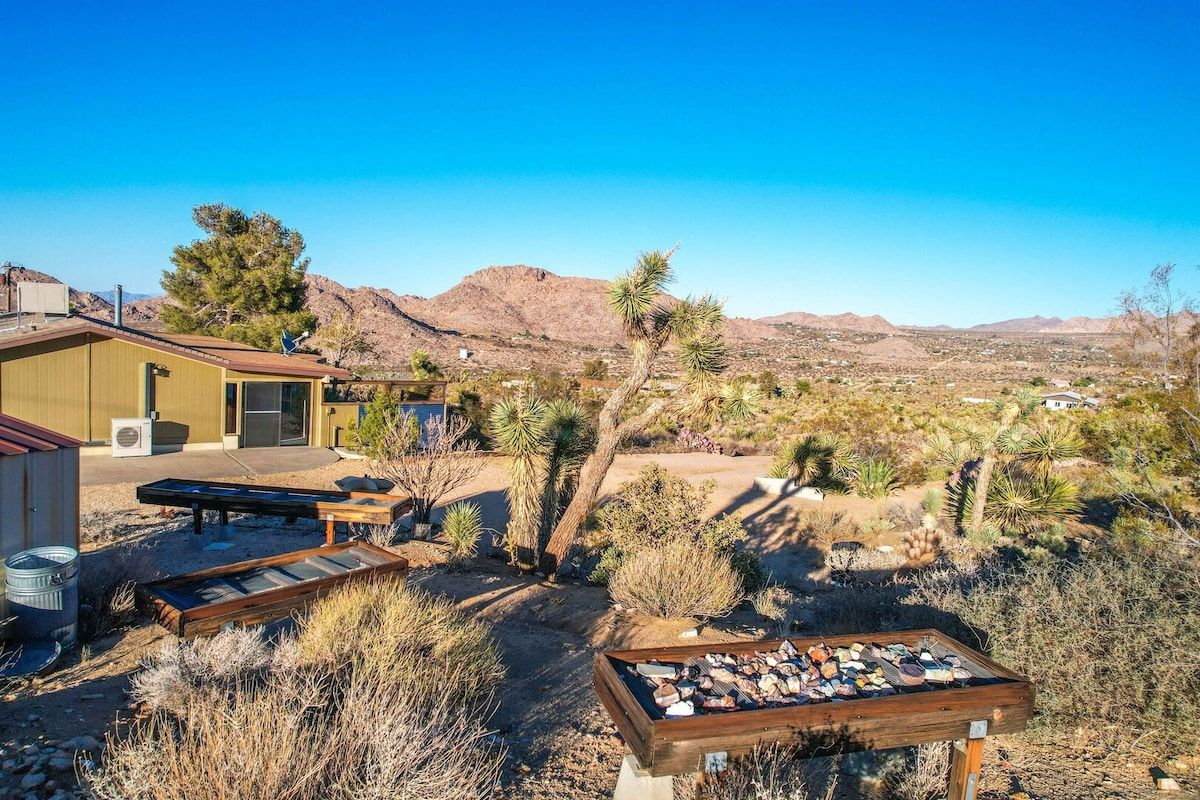 A desert landscape with a house, outdoor seating, and a display of stones.