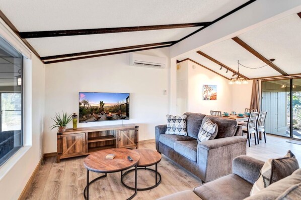 A modern living room with a sofa, coffee table, and a TV mounted on the wall.