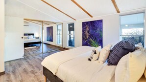 Une chambre moderne avec un grand lit, un miroir et une vue sur l’extérieur.