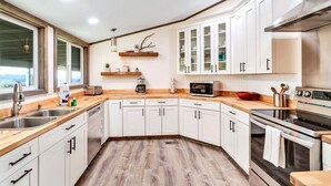 Une cuisine moderne avec des armoires blanches, un comptoir en bois et des appareils électroménagers en acier inoxydable.
