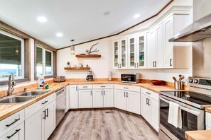 A modern kitchen with white cabinets, a wooden countertop, and stainless steel appliances.