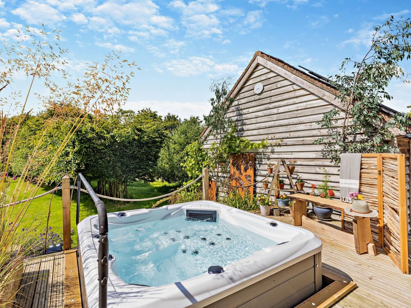 A hot tub in a wooden deck area with a rustic building in the background.