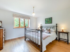 Ein Schlafzimmer mit Bett, Fenster, Schminktisch und Nachttisch.