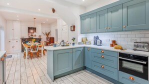 A modern kitchen with teal cabinets, white countertops, and a central island. - 7 Bed in Aberdyfi (oc-dy030) (Aberdovey)