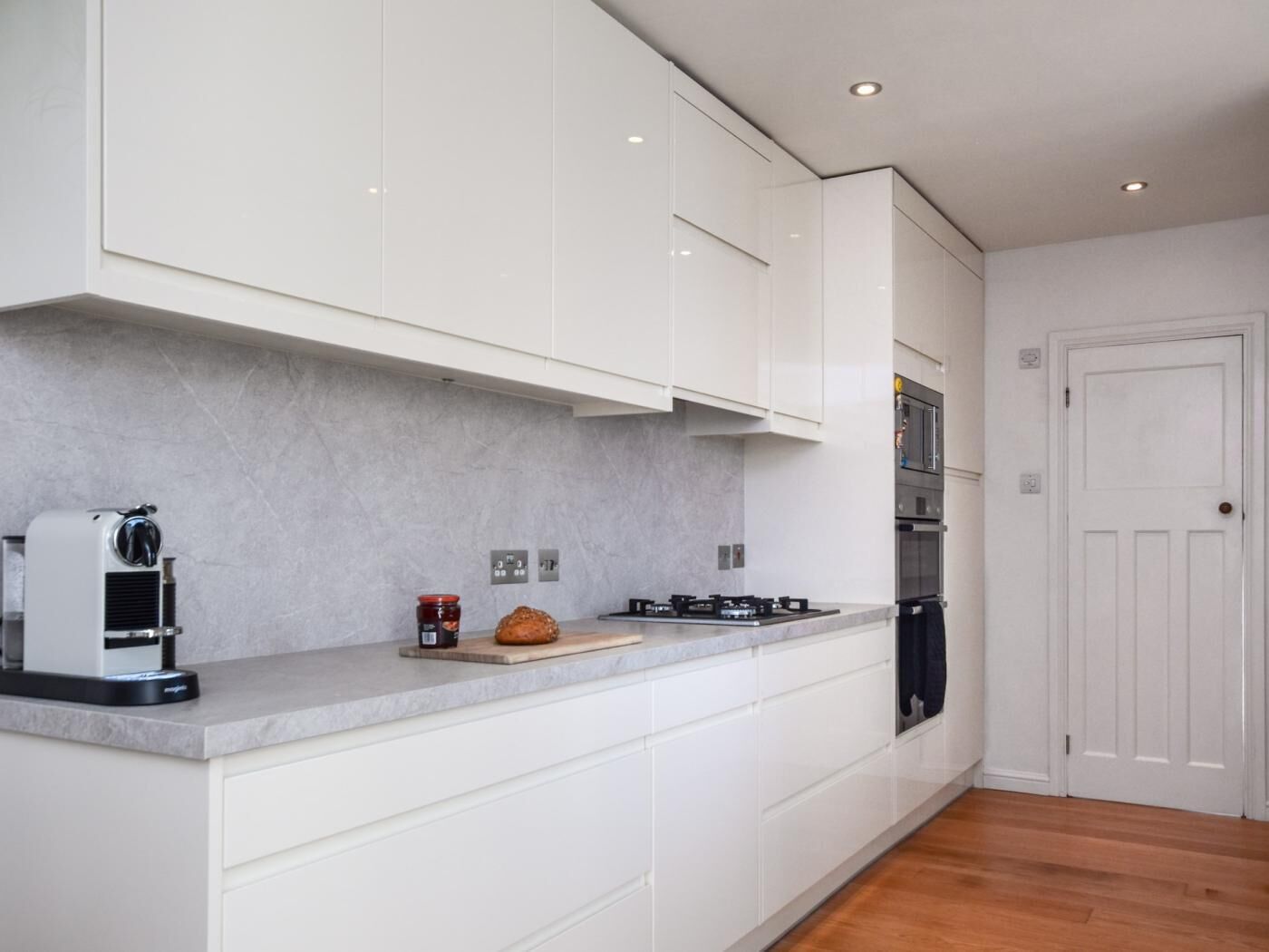 Una cocina moderna con armarios blancos, estufa integrada y una cafetera.