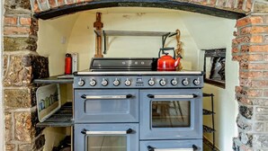 A kitchen with a brick oven, a stove, and a kettle. - 4 Bed in Bude (oc-41608) (Poundstock)