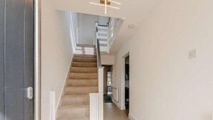 Eine Treppe führt zu einer zweiten Etage, ein Flur mit einer Tür und ein Lichtschalter an der Wand.