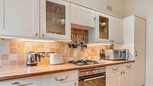 A modern kitchen with white cabinets, a gas stove, a microwave, and a kettle. - 2 Bed in Keswick (oc-94995) (Keswick)