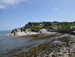 A coastal area with rocky shores, clear water, and buildings on a hillside. - 2 Bed in Woolacombe (oc-43279) (Woolacombe)