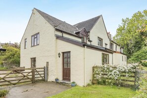 A two-story house with a white exterior, a brown door, and a visible front garden. - 2 Bed in Woolacombe (oc-43279) (Woolacombe)