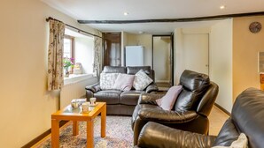 A cozy living room with a leather sofa, a wooden coffee table, and a patterned rug. - 2 Bed in Woolacombe (oc-43279) (Woolacombe)