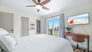 Ein Schlafzimmer mit einem Bett, einem Schreibtisch, einem Sessel, einem Fernseher und einem Deckenventilator.