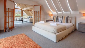 Ein Schlafzimmer mit einem großen Bett, Blick durch eine offene Tür und einem Oberlicht.
