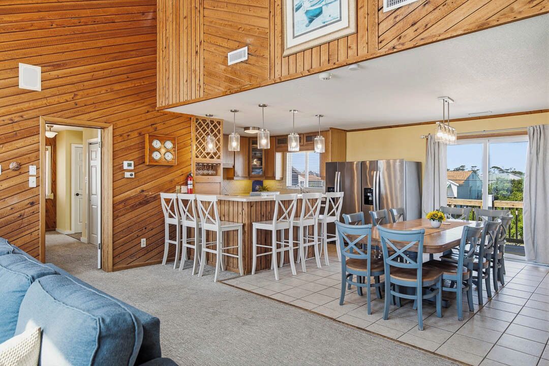 A wooden interior with a dining area, kitchen, and a large window.